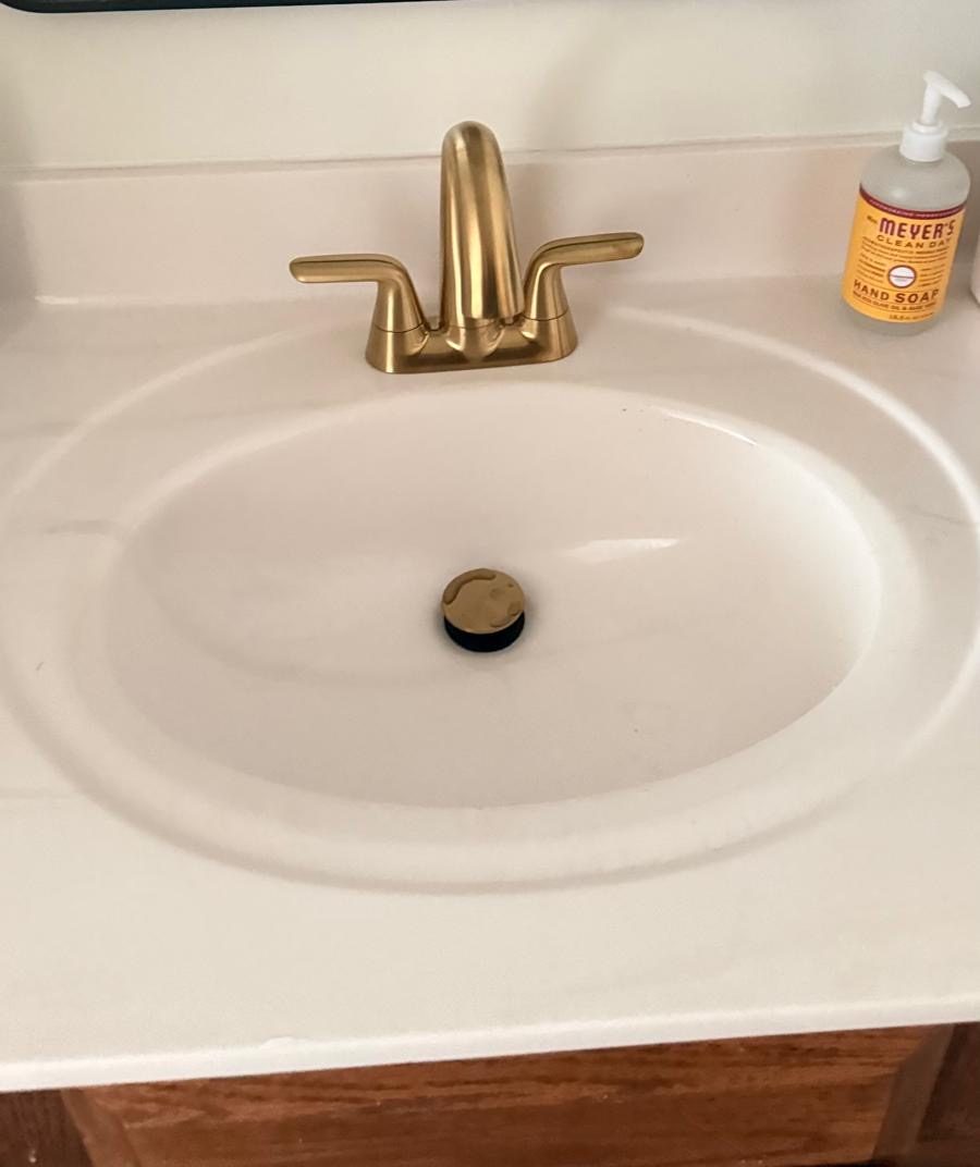 New brushed gold faucet and drain installed on a bathroom sink