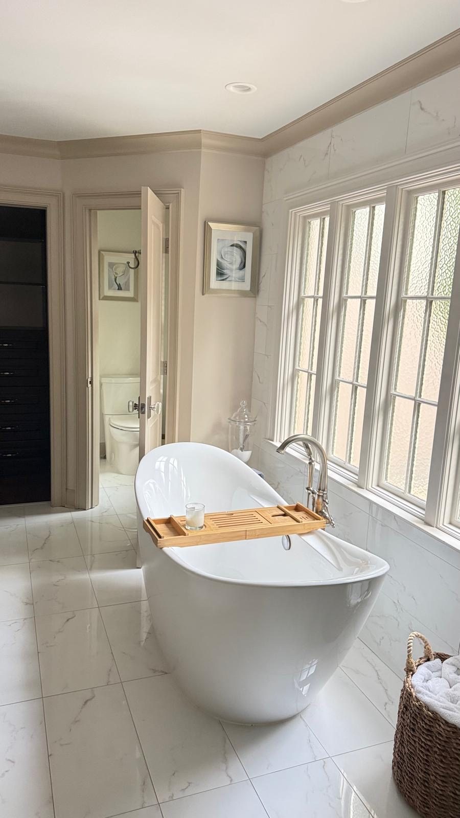 Freestanding tub with tub filler beside a window