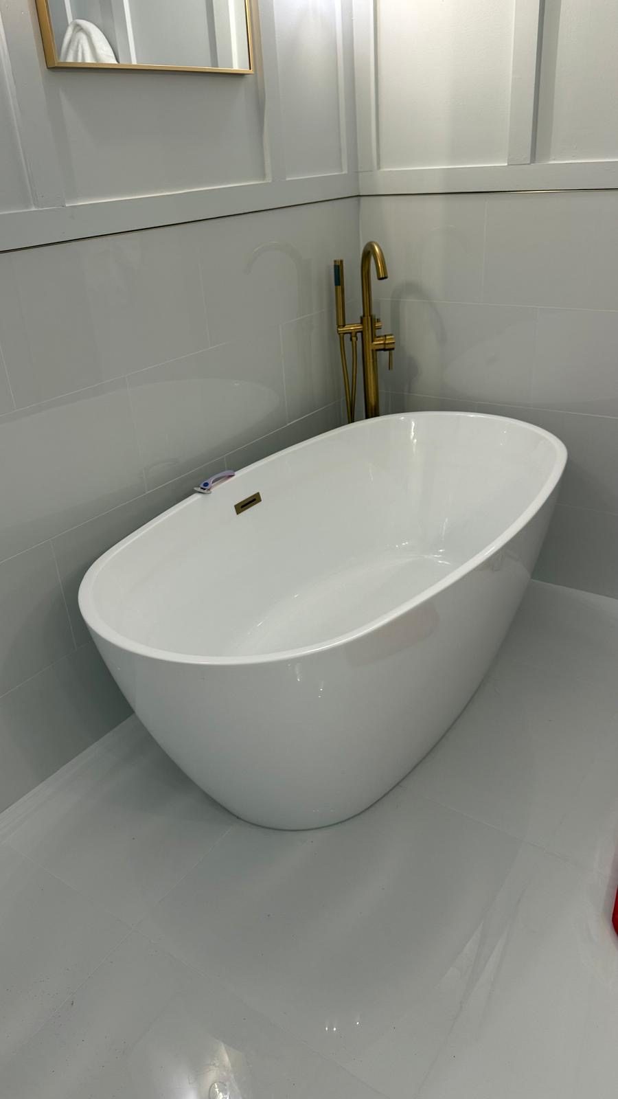 Freestanding tub with a brushed gold floor-mounted tub filler