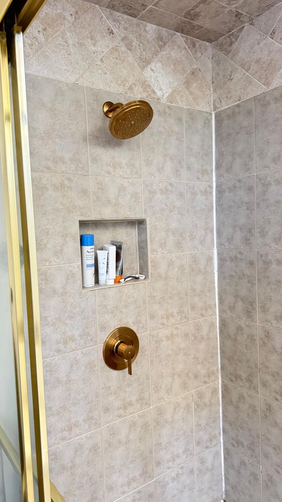 Tiled shower with brushed gold showerhead and valve